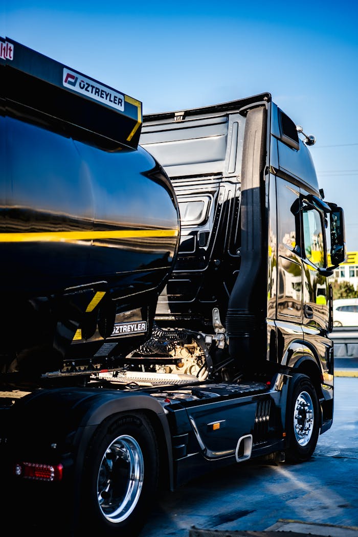 Black semi truck ready for cargo loading at an industrial dock.